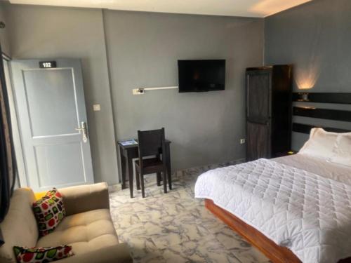a bedroom with a bed and a couch and a tv at Sunrise Center Bonapriso - 102 in Douala