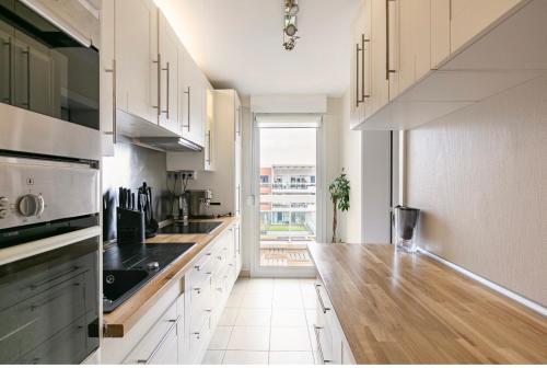 a kitchen with white cabinets and a wooden counter top at Appartement climatisé 3 étoiles T3 chic à Strasbourg avec billard et terrasse in Strasbourg