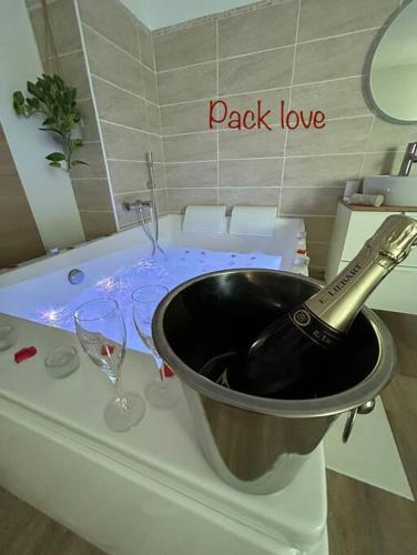 a bottle of wine in a bucket in a bath tub at Romantique Room in Muret
