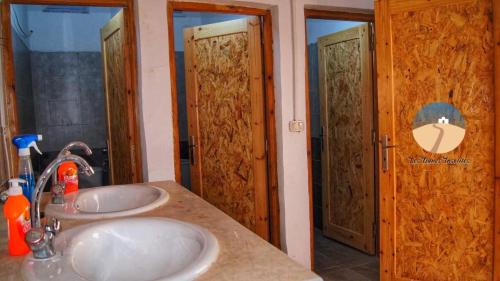 a bathroom with two sinks and two wooden doors at Luxury Camp Dunes Insolites Sabria in Sabria