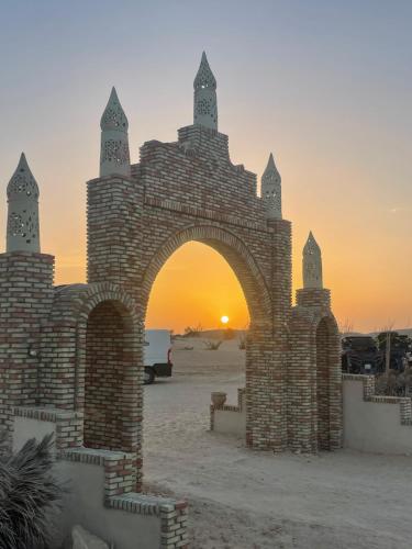 a stone arch with the sunset in the background at Luxury Camp Dunes Insolites Sabria in Sabria