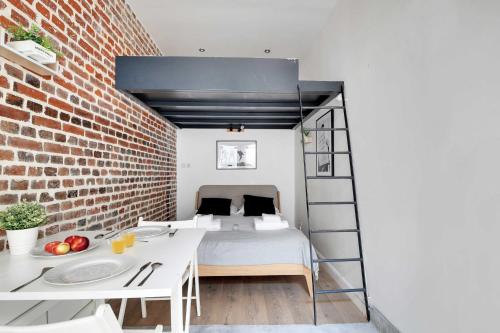 ein Schlafzimmer mit einem Bett und einer Ziegelwand in der Unterkunft Cozy studio next to Canal Saint-Martin in Paris