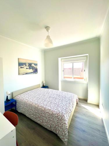 a white bedroom with a bed and a window at Estrela de Almada in Almada