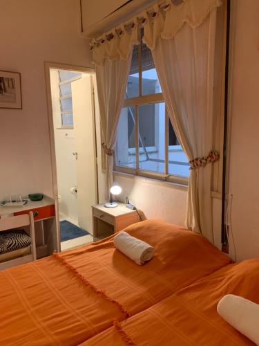 1 dormitorio con 1 cama grande de color naranja y ventana en Quartos em Copacabana, en Río de Janeiro