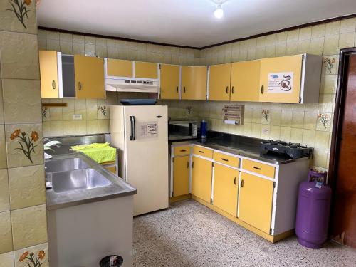 Elle comprend une petite cuisine avec des armoires jaunes et un réfrigérateur blanc. dans l'établissement Casa Purple Hostel, à Medellín