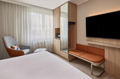 a hotel room with a bed and a flat screen tv at Courtyard by Marriott Dortmund in Dortmund