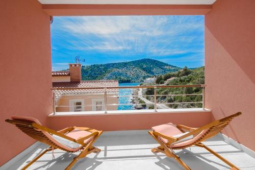 ein Balkon mit zwei Stühlen und einem großen Fenster in der Unterkunft Villa Kamelicina in Vinišće