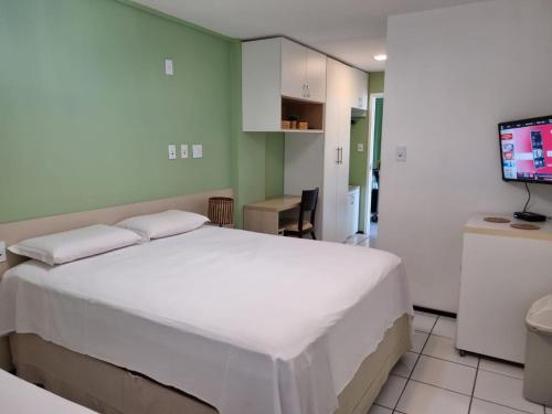 a bedroom with a large white bed and a television at Gran Lençóis Flat Residence in Barreirinhas