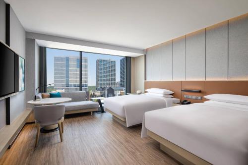 a hotel room with two beds and a view of a city at Courtyard by Marriott Jiangyin in Jiangyin