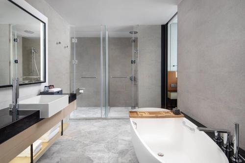 a bathroom with a tub and a shower and a sink at Courtyard by Marriott Jiangyin in Jiangyin
