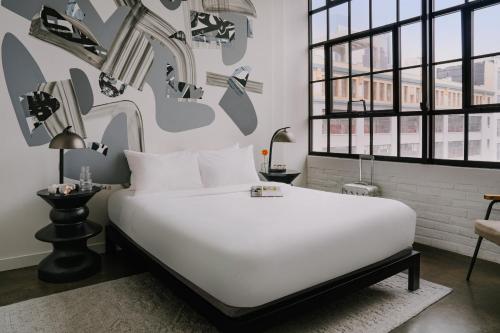 1 dormitorio con 1 cama blanca grande con zapatos en la pared en Sonder The Heid en Filadelfia