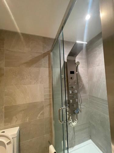 prysznic ze szklanymi drzwiami obok toalety w obiekcie Cosy Home Away from Home w mieście Seven Kings