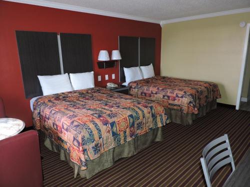Budget Inn Temple في تيمبل: سريرين في غرفة الفندق بجدران حمراء
