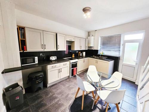 a kitchen with white cabinets and a glass table and chairs at Denton, Manchester in Denton