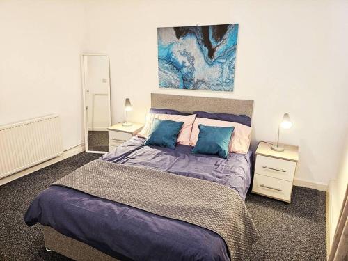 a bedroom with a large bed with blue pillows at Denton, Manchester in Denton