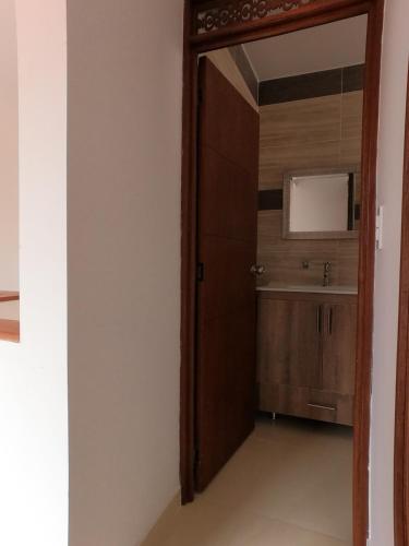 uma porta que dá acesso a uma casa de banho com um lavatório em HOTEL COLONIAL em Buga