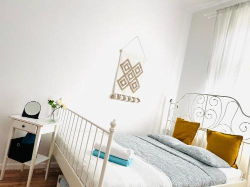 a white bedroom with a white bed with yellow pillows at Cozy Apartments and Rooms Katowice in Katowice
