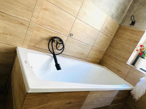 a white bath tub with a black faucet at Cozy Apartments and Rooms Katowice in Katowice