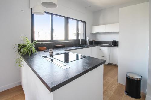 une cuisine avec des armoires blanches et un comptoir noir dans l'établissement La terrasse d'Issy - Welkeys, à Issy-les-Moulineaux