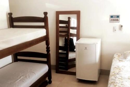a room with bunk beds and a mirror and a refrigerator at Suíte Garagem 8min do Acqualinda 1 a 5 pessoas in Andradina