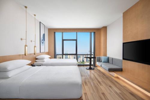 a hotel room with two beds and a flat screen tv at Fairfield by Marriott Kunming Xinying in Kunming