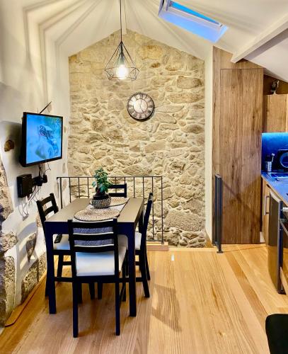 a dining room with a table and chairs and a stone wall at Casa Fina in São Pedro do Sul