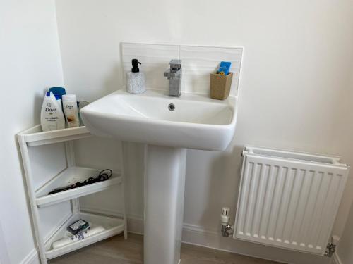 a bathroom with a white sink and a white radiator at New Comfy Family Friendly home in Canterbury in Sturry