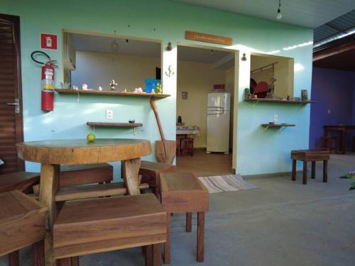 a room with a table and benches and a kitchen at Trilhas da chapada Hospedagem in Alto Paraíso de Goiás