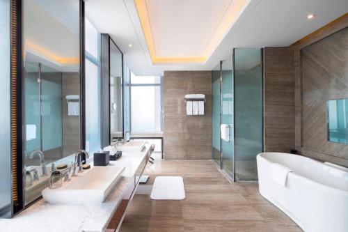 a bathroom with three sinks and a tub and mirrors at Sheraton Langfang Chaobai River Hotel in Dachang