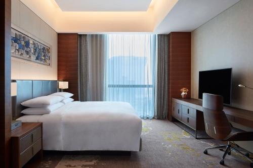a hotel room with a bed and a desk and a television at Sheraton Beijing Lize Hotel in Beijing