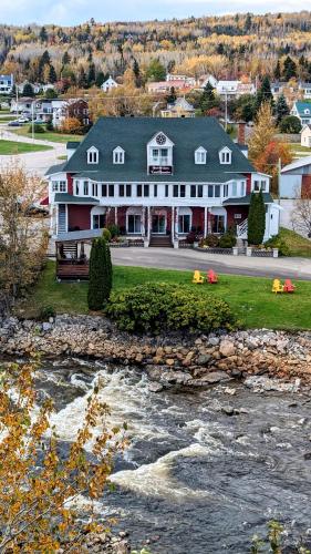a large house with a river in front of it at La Gentilhommière in Saint-Siméon