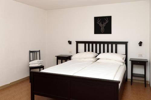 una camera da letto con un letto con lenzuola bianche e due tavoli di Apartment Il Nocciolo a Livigno