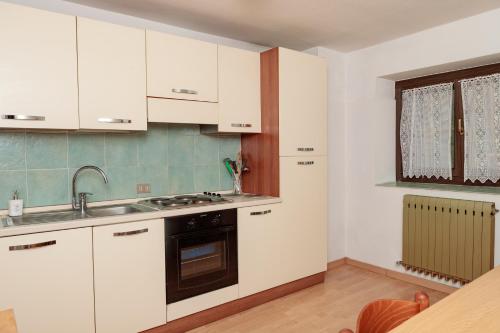 una cucina con armadi bianchi e lavandino di Apartment Il Nocciolo a Livigno
