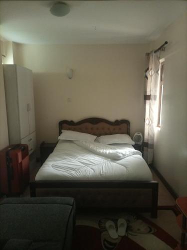a bedroom with a bed with white sheets and a window at Executive Suite Apartment in Nairobi
