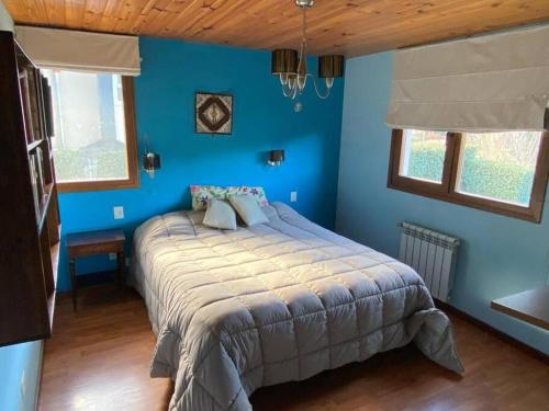um quarto com paredes azuis e uma cama em La casa de la colina em San Carlos de Bariloche