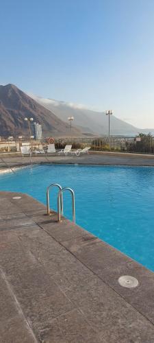 uma piscina com água azul e montanhas ao fundo em Hermoso departamento em Iquique