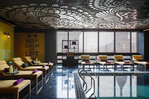 a room with a swimming pool and chairs and a ceiling with a ceilingocrinangering at Renaissance Hangzhou Northeast in Yuhang