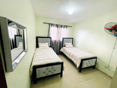 2 camas en una habitación pequeña con espejo en Oasis de Paz 4, en Jarabacoa