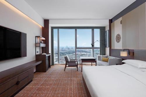 昆明市にあるSheraton Kunmingのベッドと大きな窓が備わるホテルルームです。