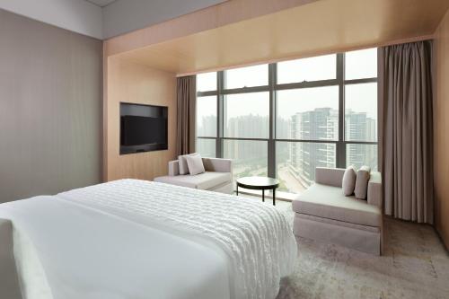 a hotel room with a bed and a large window at Le Meridien Zhongshan in Zhongshan