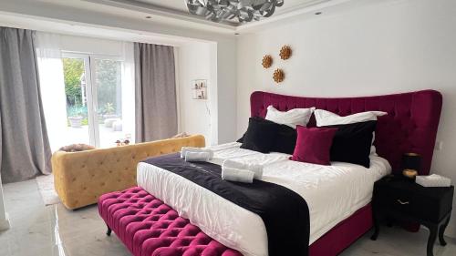 a bedroom with a large bed with a red headboard at LUXUS-RelaxDays-Apartments in Gütersloh