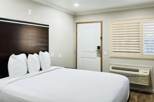 a white bed with white pillows in a room at Rodeway Inn National City San Diego South in National City