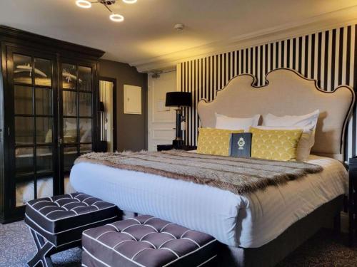 ein Schlafzimmer mit einem großen Bett mit zwei Ottomanen in der Unterkunft Hotel Vendome - BW Signature Collection in Vendôme