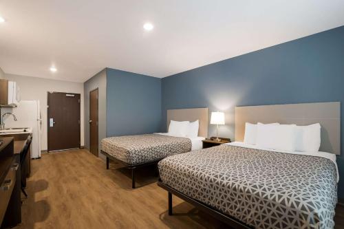 a hotel room with two beds and a kitchen at WoodSpring Suites Moreno Valley in Moreno Valley