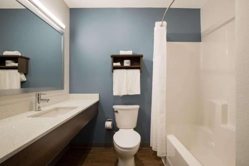 a bathroom with a toilet and a sink and a tub at WoodSpring Suites Moreno Valley in Moreno Valley