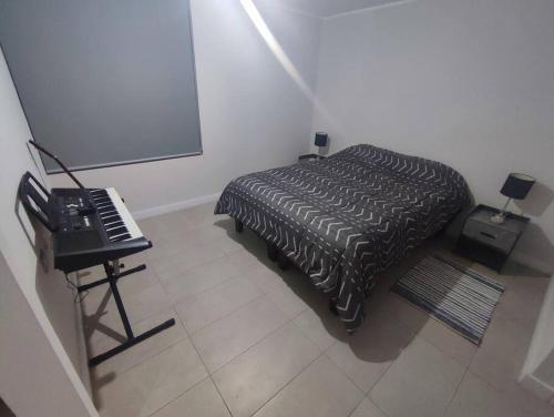 a bedroom with a bed and a piano and a screen at Cómodo Departamento 1D1B para dos personas in Santiago