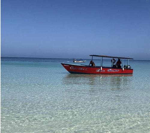 a red boat in the water on the ocean at Seacret Studios - Cozy Jamaican Retreat apts in Negril