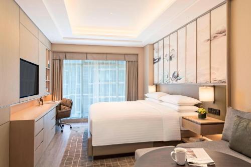 a hotel room with a bed and a television at Marriott Executive Apartments Hangzhou Yuhang in Hangzhou