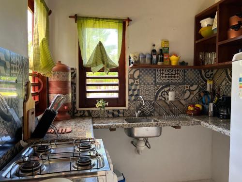 uma cozinha com um fogão, um lavatório e uma janela em Casa Vagalume - 10 minutes to secluded beach em Pôrto de Pedras