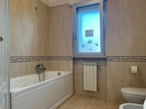 uma casa de banho com uma banheira, um WC e uma janela. em Appartamento Pescara Sud em Pescara